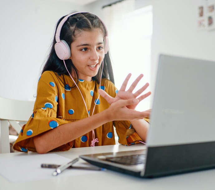 Mädchen am Schreibtisch mit einem Laptop, auf dem Norton Family gestartet wird