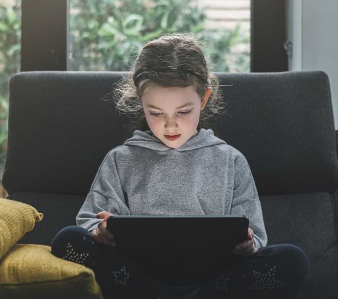 Mädchen auf dem Sofa mit einem Laptop, auf dem Norton Family gestartet wird