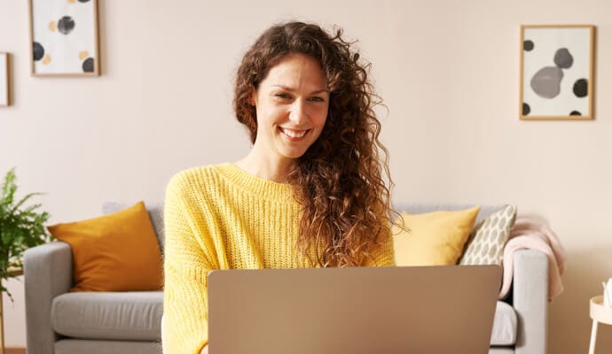 Lachende Frau mit Laptop beim Starten von Norton Safe Search